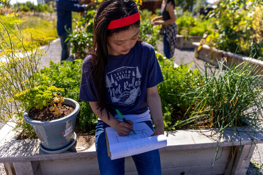 Young woman with Down syndrome planning in sunny, urban community garden