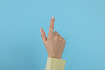 Woman pointing at something against light blue background, closeup on hand