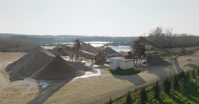 Aerial shot of machines and trucks working in a sand quarry, in France. Those are extracting and  filtering the sand.