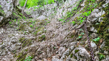 Hiking trail through a forest near mount Roethelstein near Mixnitz in Styria, Austria. The path leads through a rock formation supported by an iron chain. Via ferrata. Landscape in the Grazer Bergland
