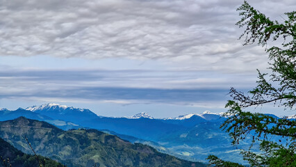 Fototapeta premium Panoramic view on the Eisenerzer Alps from below mount Roethelstein near Mixnitz in Styria, Austria. Snow capped mountain of the Ennstal Alps beyond the Grazer Bergland in Styria, Austria. Overcast