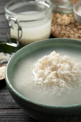 Bowl with rice soaked in water on wooden table, closeup