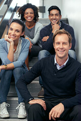 Taking a rest on the way to the top. Portrait of a group of office coworkers sitting in a stairwell.