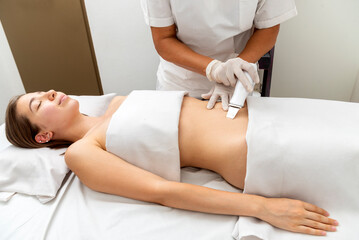 young woman in a beauty and spa center performing a beauty treatment for body and skin care with a diamond tip technique and dermapen for stretch marks