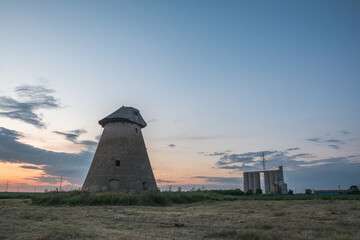 Fototapeta na wymiar Old ruined windmill at sunset