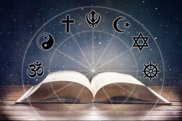 Book on wooden table with religious symbology and universe background