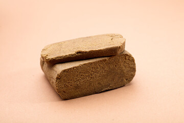 hashish tablet cut out next to large 100 gram portion, brown background