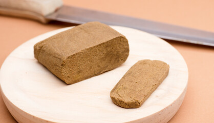 hashish large portion on wood with knife blade, brown background