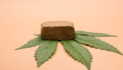 portion hashish tablet with marijuana leaf, bronw background
