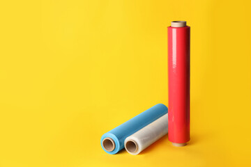Different plastic stretch wrap films on yellow background, space for text