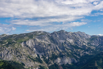 Fototapeta premium Panoramic view on the alpine mountain chains in Styria, Austria, Hochschwab region. Hills overgrown with small bushes, higher parts rocky and bare. Sunny summer day. Serenity. Hiking in Alps, Tragoess