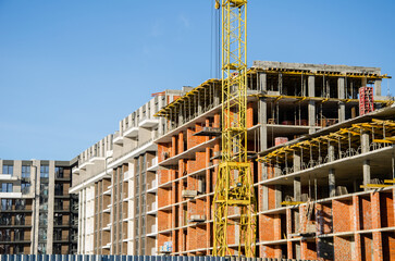 Construction site background. Hoisting cranes and new multi-storey buildings. Industrial background. brick building.
