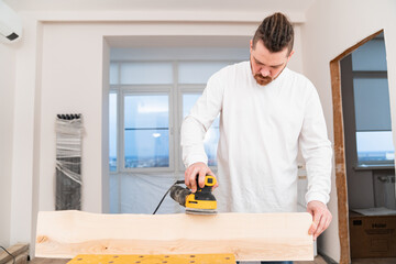 carpenter working on wood grinding machine. grinds and polishes wood. 