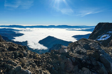 A massive cliff of mount Eisenerzer Reichenstein in Styria, Austria, Europe. Austrian Alps. Bare mountain ridges with view on the cloud covered Ennstal Valley. Hiking trail, Wanderlust. Sunny day
