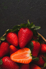 Fresh strawberries in a bowl on a darken table with a low key scene.