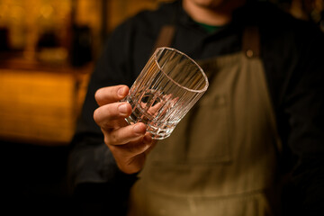 hand of bartender hold old-fashioned cocktail glass.