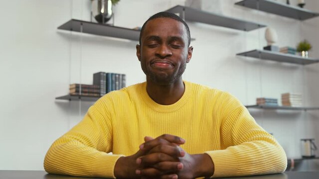 Smiling man communicating by videoconference at home. Attractive man telling a story