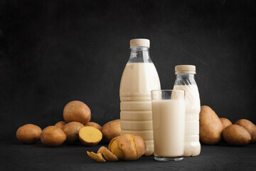 Potato milk glass and bottles on dark background. Alternative vegan plant based non dairy drink. Healthy vegetarian and vegan drink concept with copy space