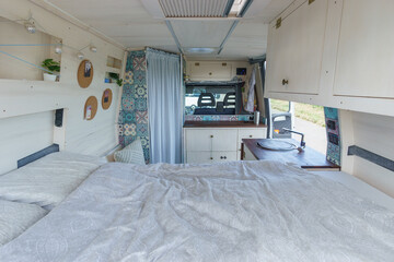bright white and brown interior of a self made camper van transporter with bed, cupboard and kitchen sink - obrazy, fototapety, plakaty