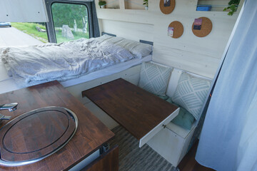 bright white and brown nterior of a self made camper van transporter with bed, bench and extendable...