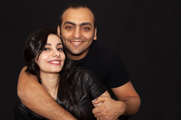 Family portrait of a young couple on a black background. Studio Portrait