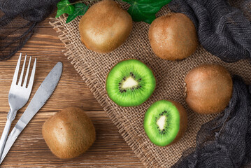 Set of fresh whole and cut fresh kiwifruit on wooden table with cutlery