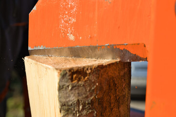 Close-up shot of a hydraulic wood splitter cutting fire wood on a sunny day