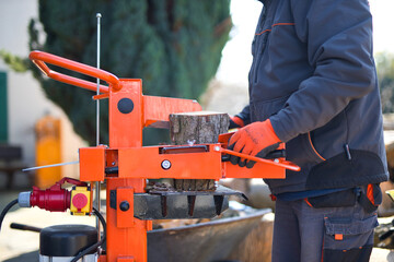 Close-up shot of a hydraulic wood splitter cutting fire wood on a sunny day