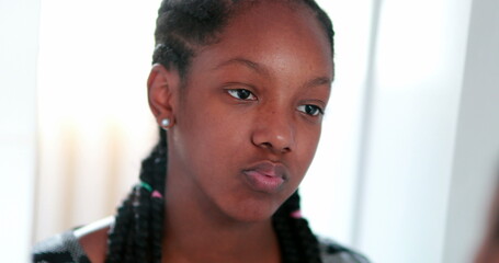 African girl looking at herself in mirror. Teenage adolescent girl standing in face reflection