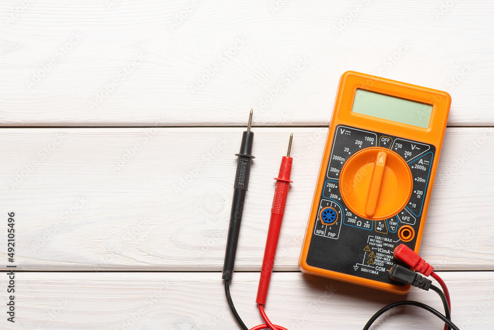 Wall mural electric multimeter on the wooden table flat lay background with copy space.