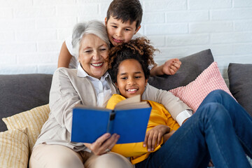 Multiethnic family. Grandparent teaching children to read for school