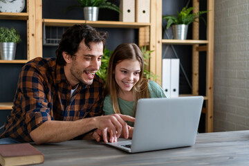 Happy father helping his teenager daughter in homeschooling. People, family technology concept.
