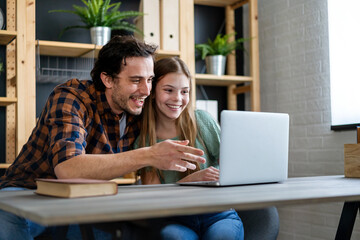 Happy father studying with teenage child girl using laptop at home schooling