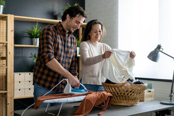 Young couple at home doing household chores and ironing together