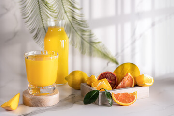 Glass of fresh orange juice with fresh fruit on a wooden table Still life with fresh orange juice in a glass with splashes and drops. The juice is pouring from the decanter into the glass