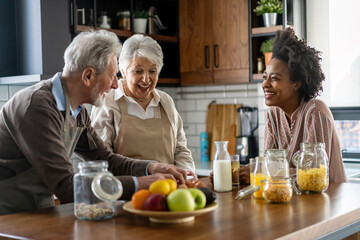 Happy multiethnic family with senior parents having fun and talking in kitchen.