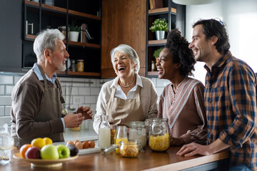 Multi generation multiethnic family having fun, talking around a festive kitchen table.