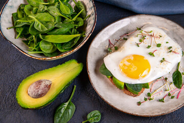 Sandwich with avocado, egg, spinach, microgreens and sesame. Healthy food rich in fiber, healthy fats, vitamins, trace elements.