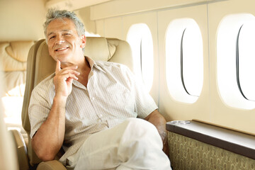Travelling in style. Portrait of a handsome senior man sitting in an airplane with a smile.