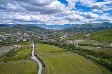 A mountain valley with a road through mown fields, vineyards and settlements. Shooting from a drone.