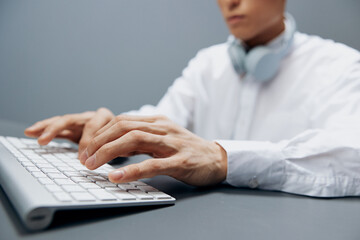 man in headphones hands on keyboard office work close-up Gray background