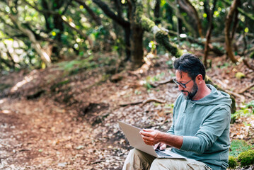 Modern people working outdoor with laptop computer and wireless internet data connection. Alternative online job and free travel lifestyle for remote worker people. Handsome male using computer