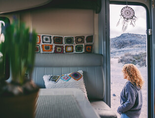 Woman walking outside her camper van. View from interior. Knit decorations inside. Concept of travel and rv motorhome vanlife lifestyle with traveler female people enjoying outdoors