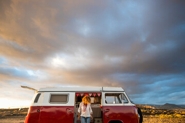 People travel and enjoy vanlife adventure lifestyle. Standing woman against a red classic vintage...
