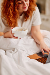 A redhead girl eating breakfast in the bed. A ginger girl sitting in her bed in the bedroom and...