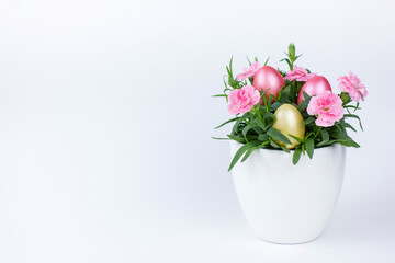 Easter eggs with carnation flower in a flowerpot on a white background.