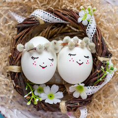 White Easter eggs with cute faces in the nest.