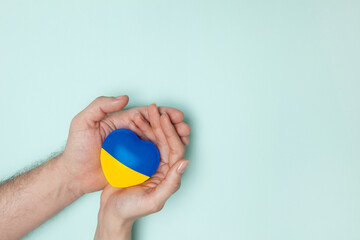 Heart with print the national flag of ukraine in female and male hands. Flat lay. Copy space.