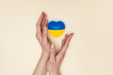 Heart with print the national flag of ukraine in female hands. Flat lay. Copy space.