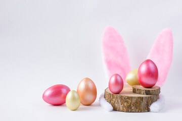 Easter Wooden colored eggs on saw cut of a tree with feathers and bunny ears.
